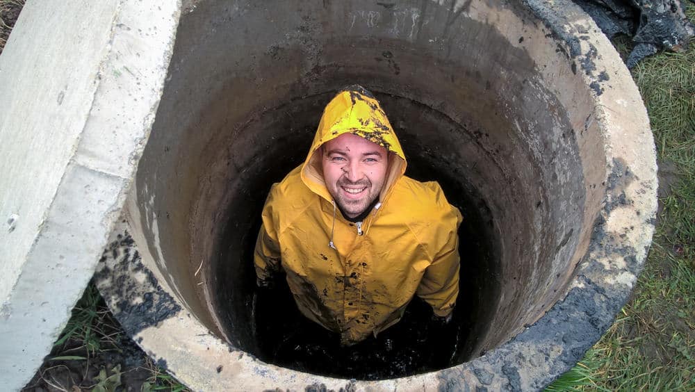 Sewer worker performing quality cesspool service on Long Island, NY with professional equipment at a residential site
